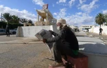 Un Tunisien lit le journal devant la sculpture de la cariole de M. Bouazizi, le 27 octobre 2020 à Sidi Bouzid