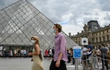 Des touristes passent devant la Pyramide du Louvre conçue par l'architecte Ieoh Ming Pei, le 15 août 2020 à Paris