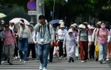 Un guide marche devant un groupe de touristes qu'il accompagne à Pékin le 20 mai 2025