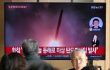 Des passants regardent une télévision diffusant un journal télévisé avec des images d'archives d'un essai de missile nord-coréen, dans une gare de Séoul, le 7 novembre 2025