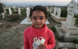 Yasmine al-Cham, survivante du tremblement de terre de février 2023, apporte des fleurs au cimetière où les victimes ont été enterrées, à Jindayris, au nord-ouest de la province d'Alep, le 2 février 2024 en Syrie