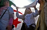 Des Algériennes sous un grand drapeau du pays lors de la manifestation d'enseignants et d'élèves contre l'extension du quatrième mandat d'Abdelaziz Bouteflika, le 13 mars 2019 à Alger