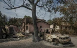 Une voiture calcinée devant une maison détruite par l'incendie, au Porge, dans le sud-ouest de la France, le 31 juillet 2026