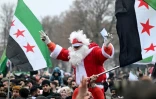 Un participant en costume en Père Noël au milieu de la foule de Syriens rassemblés à Berlin, le 8 décembre 2024 en Allemagne, pour célébrer la fin du régime du dictateur syrien Bachar al-Assad après que des groupes rebelles ont pris le contrôle de la capitale Damas