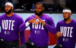 LeBron James (c) genou à terre contre les violences policières faites aux Noirs et tee-shirt incitant à voter, lors d'un match avec avec les Lakers contre Denver, le 22 septembre 2020 à Buena Vista en Floride