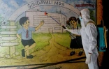 Un agent désinfecte un mur d'une école avant sa réouverture, à Bombay, le 23 janvier 2022. Des écoles ont été fermées à titre préventif pour enrayer la propagation du Covid-19