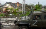 Des soldats russes à bord d'un véhicule militaire marqué de la lettre Z passent devant des maisons détruites à Marioupol, le 18 mai 2022 en Ukraine