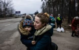 Une femme avec son enfant dans les bras quitte la ville d'Irpin, au nord-ouest de Kiev, le 7 mars 2022.