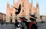Un homme au visage couvert d'un masque protecteur joue avec des pigeons devant la cathédrale de Mialn en Italie, le 24 février 2020