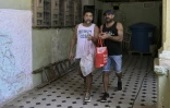 Leandro Wanton (à gauche) et Roberto Ronda, qui ont lancé un petit commerce de repas, vont livrer à pied une commande, le 31 juillet 2026 à La Havane
