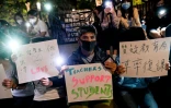 Des manifestants tiennent des pancartes et des téléphones portables alors qu'ils prient pour les étudiants barricadés sur le campus de l'université polytechnique de Hong Kong, le 19 novembre 2019