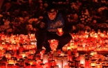 Un gendarme roumain place des bougies en mémoire des victimes de l'incendie d'une discothèque à Bucarest le 2 novembre 2015