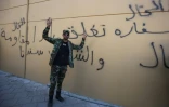 Un membre du Hachd al-Chaabi, coalition de paramilitaires dominée par des factions pro-Iran, fait le V de la victoire devant un graffitti en arabe sur le mur de l'ambassade des Etats-Unis à Bagdad, qui affirme : "l'ambassade américaine est fermée sur ordre du peuple", durant un rassemblement de  protestation le 31 décembre 2019