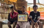 Somari Negi (c), veuve de Rameshwar Negi, tué en 2024 par les paramilitaires qui le soupçonnaientt d'être un rebelle maoïste, montre une photo de son mari, aux côtés de ses fils, à Marda, dans le district de Bastar de l'Etat de Chhattisgarh, le 14 mars 2025 dans le centre de l'Inde