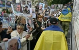 Des prisonniers de guerre ukrainiens libérés enveloppés dans le drapeau national passent devant une foule tenant des portraits de leurs proches et amis disparus ou capturés, à leur arrivée après un échange de prisonniers dans la région de Tcherniguiv, le 26 juin 2025, en Ukraine