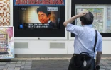 Un passant devant un écran diffusant la nouvelle de l'assassinat par balles de l'ex Premier ministre Shinzo Abe, à Tokyo le 8 juillet 2022