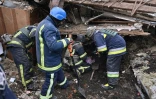 Des membres des services de secours cherchent dans les décombres d'un immeuble, le 8 janvier 2024 à Zmiiv, dans la région de Kharkiv, en Ukraine