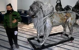 Le sculpteur Ehtisham Jadoon à côté de sa création, un lion à la crinière d'acier torsadé réalisé à partir de ferraille, dans son atelier situé à la périphérie d'Islamabad, le 29 décembre 2025 au Pakistan