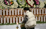 Une personne se recueille devant un autel commémoratif pour les victimes de l'accident d'avion de Jeju Air, au parc sportif de Muan en Corée du Sud, le 30 décembre 2024