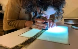 Courtney Holschuh utilise une loupe pour regarder la pellicule d'un film, au Centre national de conservation audiovisuelle de la Bibliothèque du Congrès à Culpeper, le 2 avril 2026 en Virginie