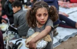 Une fillette palestinienne porte de la nourriture tandis que des personnes se rassemblent pour un repas de rupture du jeûne du ramadan à Beit Lahia, dans le nord de la bande de Gaza, le 15 mars 2025