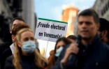 Une pancarte "Fraude électorale au Venezuela", brandie derrière le leader de l'opposition vénézuélienne Leopoldo Lopez (à droite) durant une manifestation réclamant un référendum au Venezuela, le 6 décembre 2020 à Madrid