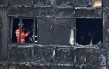 Des pompiers inspectent ce qu'il reste de la tour Grenfell ravagée par un incendie, le 16 juin 2017 à Londres