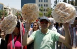 Des Jordaniens brandissent du pain sur lequel est écrit "corruption = faim" lors d'une manifestation contre l'austérité et la cherté de la vie, le 6 juin à Amman