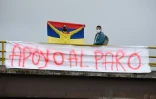 Un homme porte un drapeau colombien derrière une banderole en soutien à la mobilisation contre le gouvernement de droite du président Ivan Duque, le 5 mai 2021 à Subia