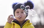 Un enfant ukrainien fait des bulles de savon après avoir traversé la frontière ukraino-roumaine à Siret, dans le nord de la Roumanie, le 20 mars 2022