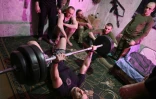 Oleksandre, commandant d'une unité d'assaut dans la 93ème brigade, soulève des haltères avec ses hommes, dans la région de Donetsk, le 20 février 2025 en Ukraine