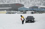 Un homme essaie de dégager sa voiture prise dans la neige, le 17 avril 2025 à Steg, dans le canton du Valais, en Suisse