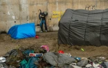 Des tentes de migrants devant une oeuvre de l'artiste britannique Bansky photographiée le 12 décembre 2015 et située à l'entrée de la "Jungle" de Calais, représente Steve Jobs (Apple), qui porte un baluchon et un vieil ordinateur