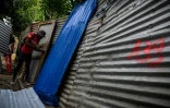 Un homme démonte des plaques de tôle dans le bidonville "Talus 2", dans le nord de Mayotte, promis à une démolition imminente, le 21 mai 2023
