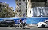 Un cycliste passe devant un immeuble endommagé par un missile iranien, le 8 mars 2026 à Tel-Aviv 
