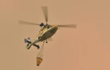 Un hélicoptère va larguer une charge d'eau sur un feu de forêt à Bargo, le 21 décembre 2019 en Australie