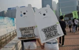 Deux femmes portent sur leur dos des panneaux en forme d'ours polaires proclamant "SDF et affamé" ou encore "s'il vous plaît, à l'aide", lors d'une marche pour le climat à Hong Kong, le 29 novembre 2015