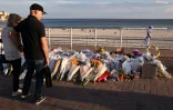 Des personnes regardent le 20 décembre 2025 les fleurs déposées près de la plage de Bondi à la mémoire des victimes de l'attentat de Sydney