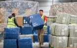 Des employés d'une société de logistique transportent des colis de fret aérien dans un entrepôt de l'aéroport Roissy-Charles de Gaulle, au nord de Paris, le 29 avril 2025