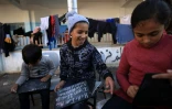 Des enfants palestiniens déplacés écrivent sur des ardoises lors d'une leçon d'anglais dans une école devenue camp de déplacés à Rafah, dans le sud de la bande de Gaza, le 29 novembre 2023