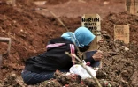Une femme se recueille sur la tombe d'un proche décédé du Covid-19 dans un cimetière de Bekasi (Indonésie) le 28 janvier 2021.