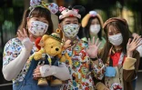 Des visiteurs portant des masques attendent d'entrer dans le Disneyland de Shanghai qui rouvre le 11 mai 2020
