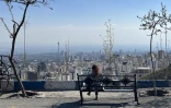 Une femme est assise sur un banc donnant sur la ville, au parc Pardisan à Téhéran, le 22 avril 2026.
