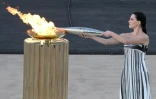 L'actrice grecque Mary Mina dans le rôle d'une grande prêtresse allume la flamme olympique lors de la cérémonie de remise aux orgnaisateurs des JO-2024 de Paris, le 26 avril 2024 à Athènes