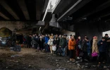 Des habitants attendent leur tour pour traverser un pont détruit pour quitter la ville d'Irpin, au nord-ouest de Kiev, le 7 mars 2022.