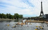 Des baigneurs nagent dans la Seine sur un site aménagé sur le bras de Seine de Grenelle, près de la tour Eiffel (en arrière-plan), à Paris, le 5 juillet 2025