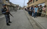 Un membre des forces de sécurité irakiennes se tient le 12 mai 2018 devant un bureau de vote de la ville de Mossoul, dans le nord de l'Irak, où des gens attendent de pouvoir voter pour les élections législatives 