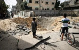 Des enfants palestiniens devant un cratère causé par dles bombardements israéliens dans une rue de Rafah, dans le sud de la bande de Gaza, le 18 mai 2024