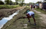 Un homme se lave les cheveux à proximité d'un cours d'eau polluée du quartier 28 de octubre, à La Matanza, banlieue pauvre de Buenos Aires, le 15 avril 2021
