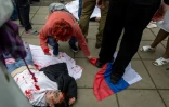 Une femme tente de récupérer un drapeau russe piétiné par un activiste pro-ukrainien lors d'une manifestation contre l'invasion russe de l'Ukraine, au mausolée des soldats soviétiques à Varsovie, le 9 mai 2025 en Pologne